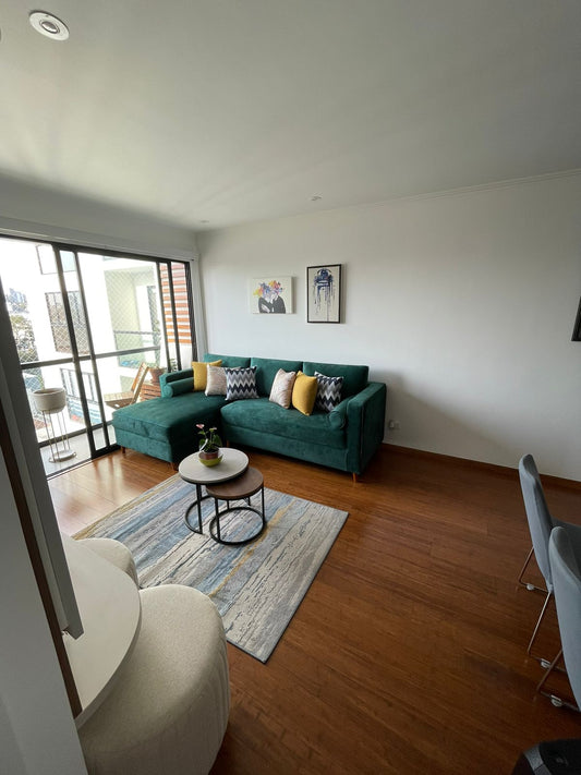 Mueble seccional Americano en tela verde esmeralda con baúl, vista de sala - Deco Muebles